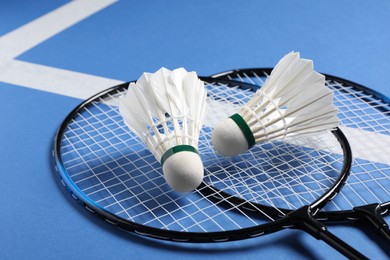 Feather badminton shuttlecocks and rackets on blue background, closeup