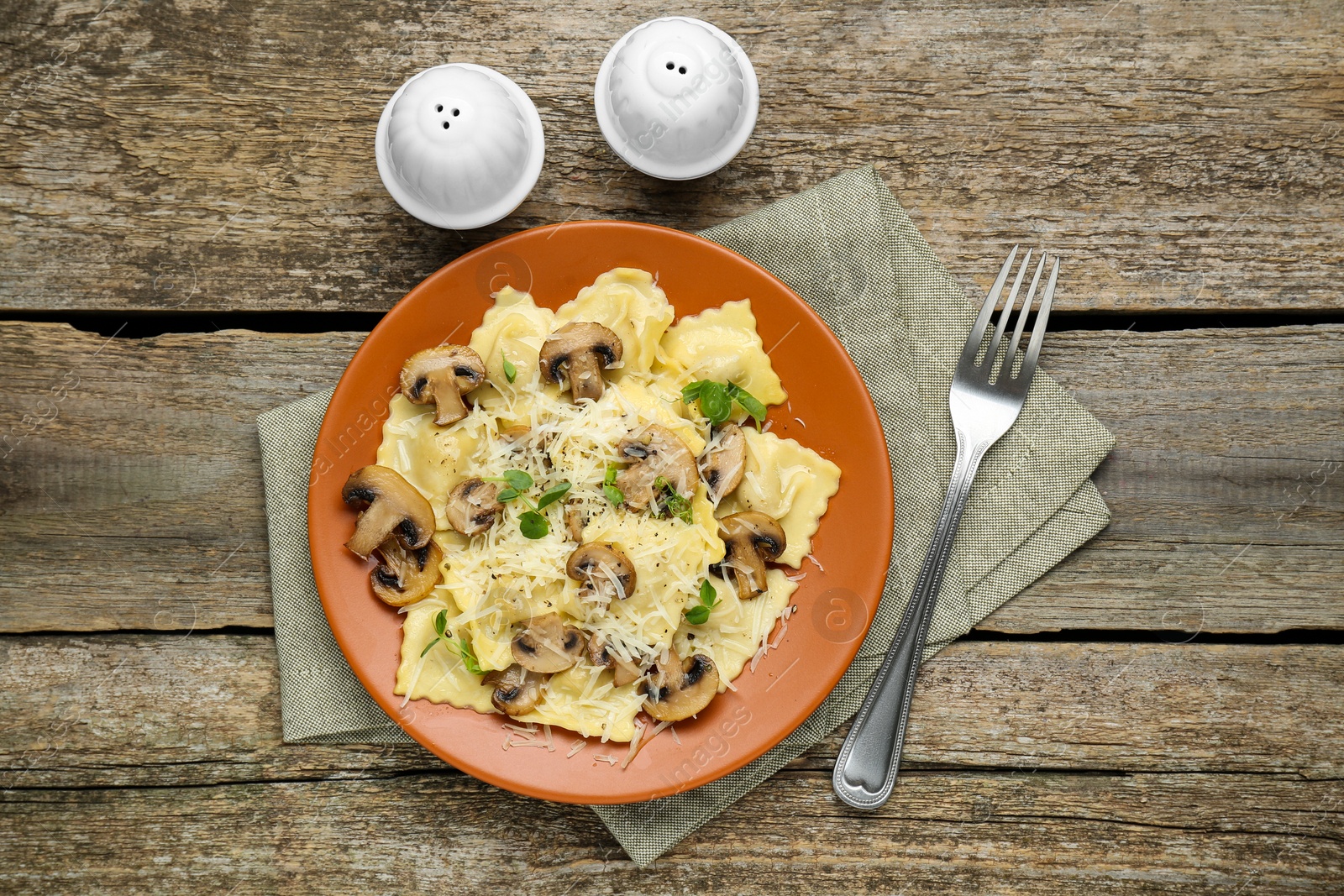 Photo of Delicious ravioli with mushrooms and cheese served on wooden table, flat lay