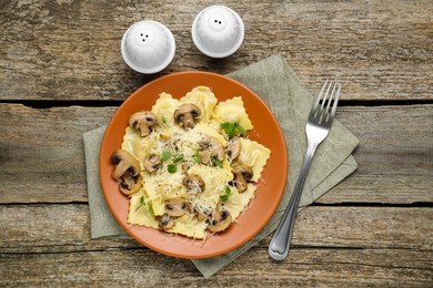 Delicious ravioli with mushrooms and cheese served on wooden table, flat lay