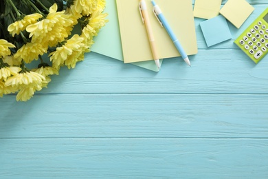 Beautiful flowers and stationery on light blue wooden background, flat lay with space for text. Teacher's Day