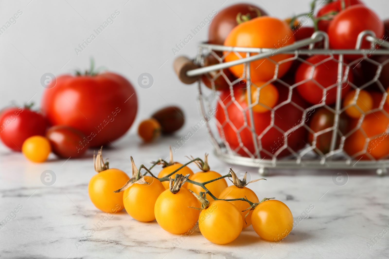 Photo of Branch of yellow cherry tomatoes on marble table