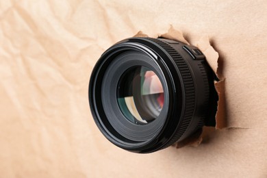 Hidden camera lens through torn in paper, closeup