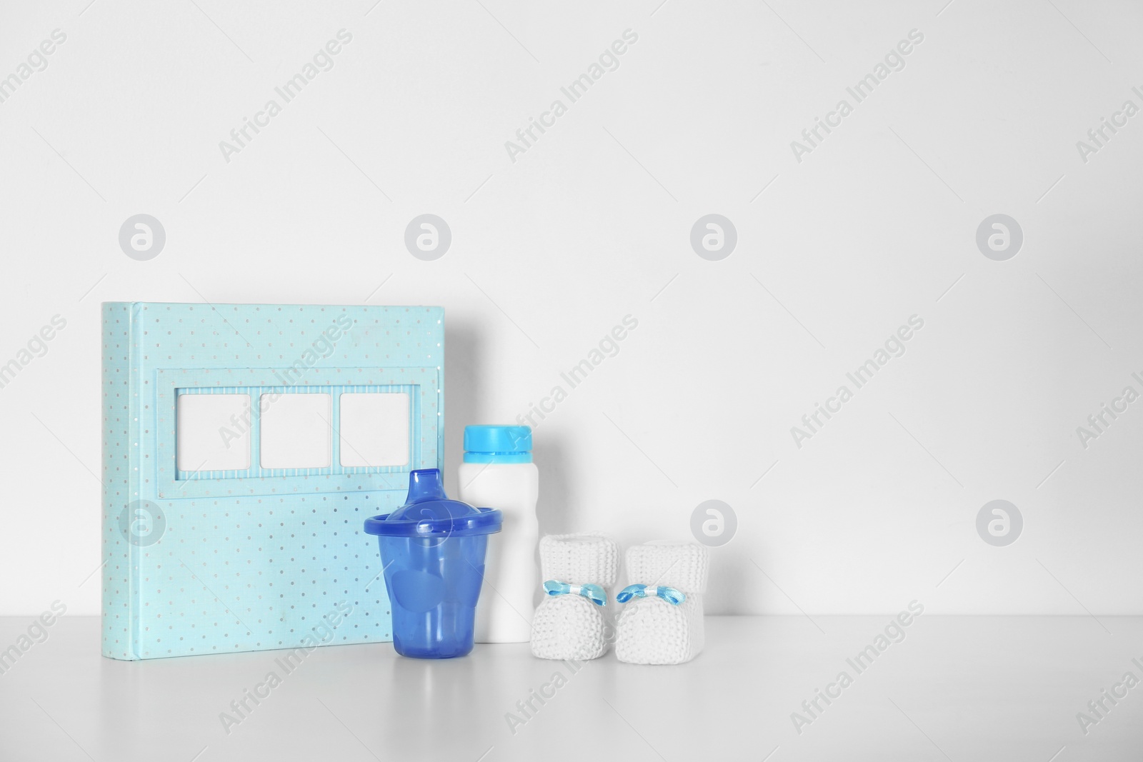 Photo of Composition with photo album for baby room interior on table near white wall