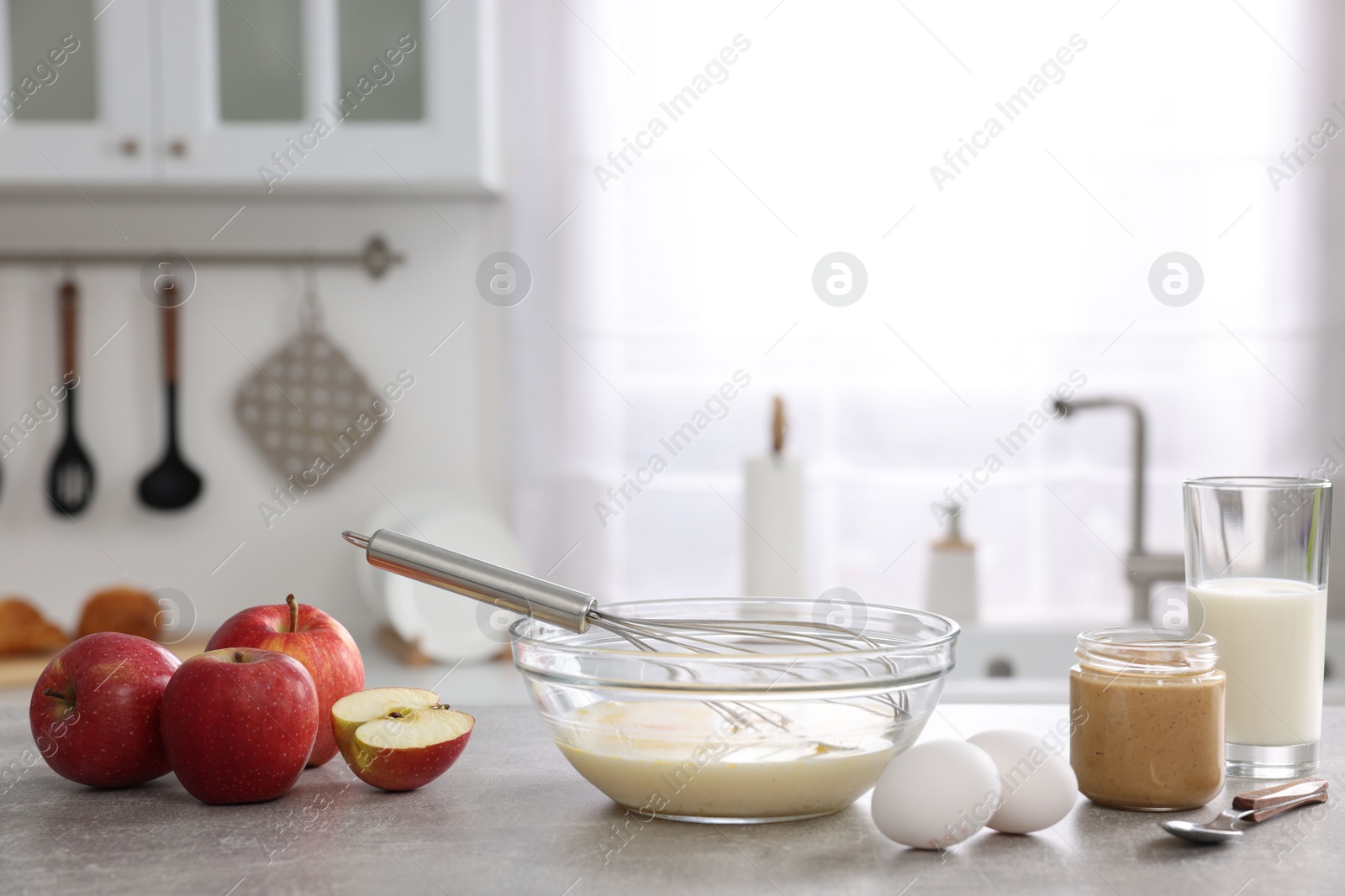 Photo of Whisk, bowl, beaten eggs and other ingredients on grey table indoors, space for text