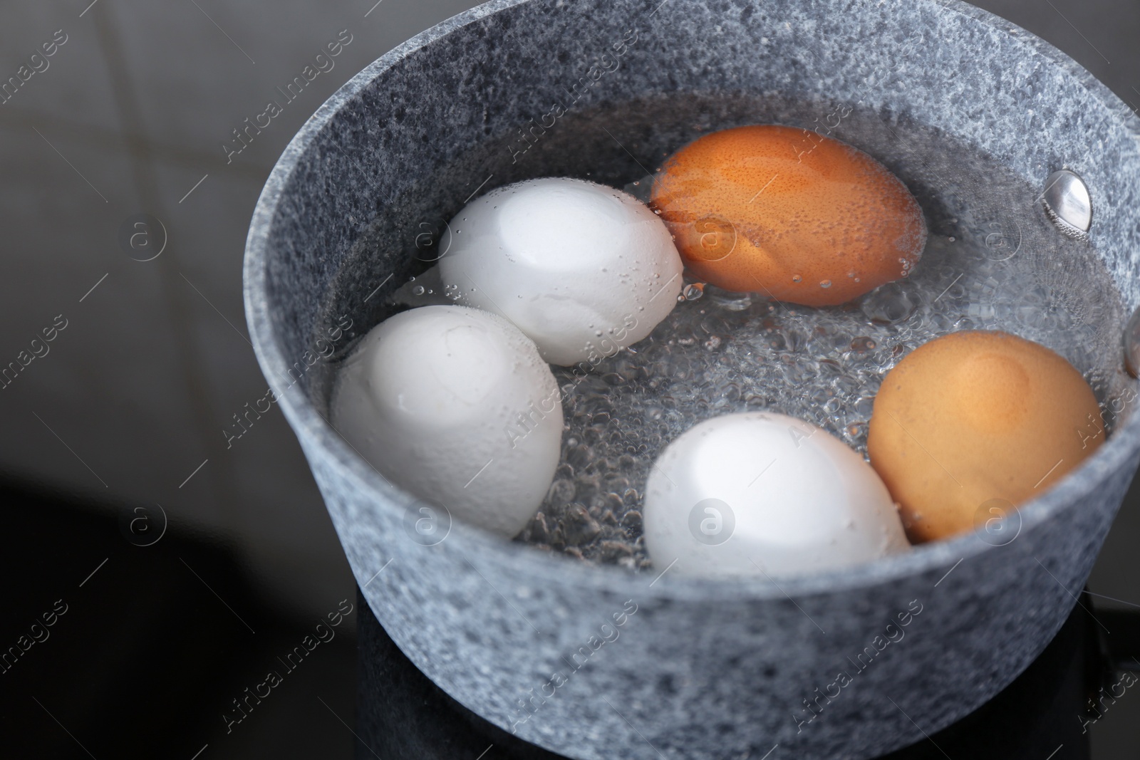 Photo of Chicken eggs boiling in saucepan on electric stove, closeup