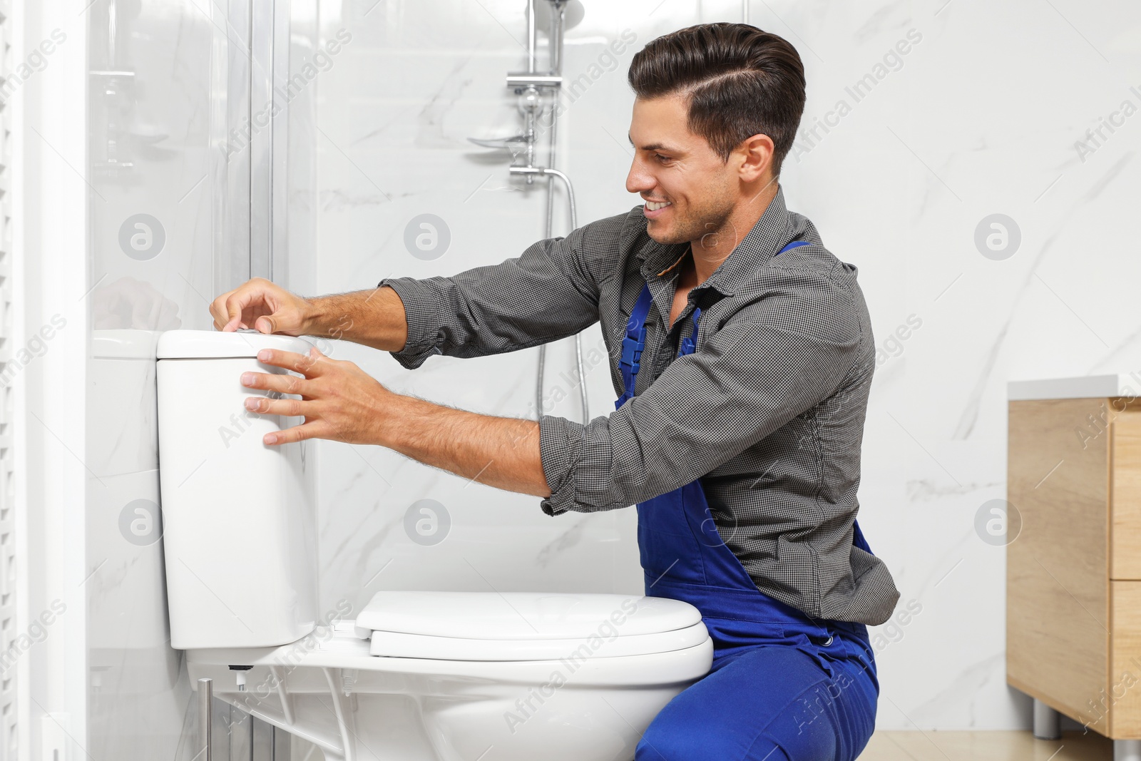 Photo of Professional plumber working with toilet bowl in bathroom