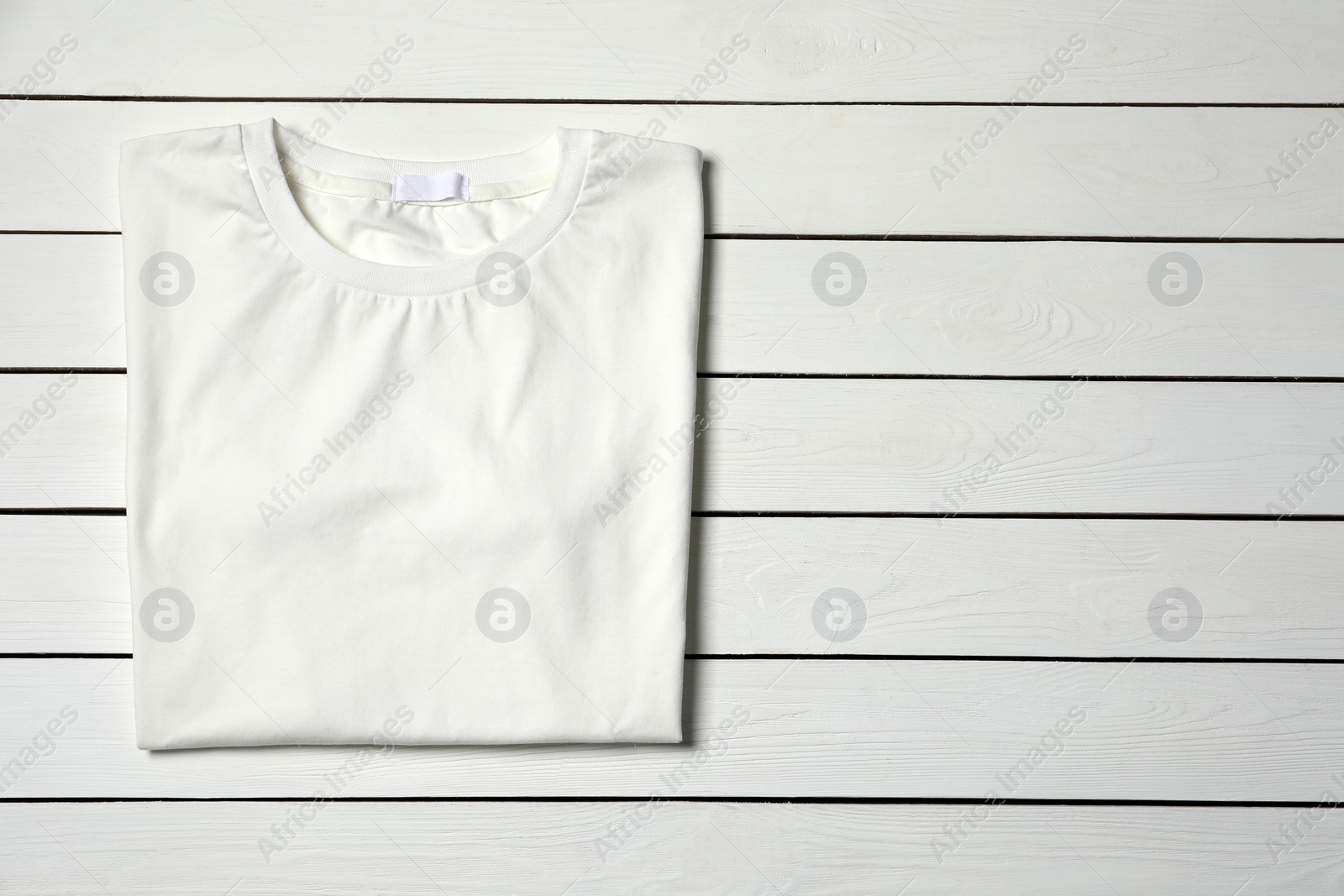 Photo of Stylish T-shirt on white wooden table, top view. Space for text