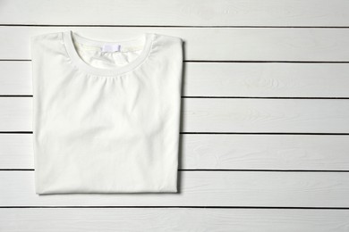 Photo of Stylish T-shirt on white wooden table, top view. Space for text