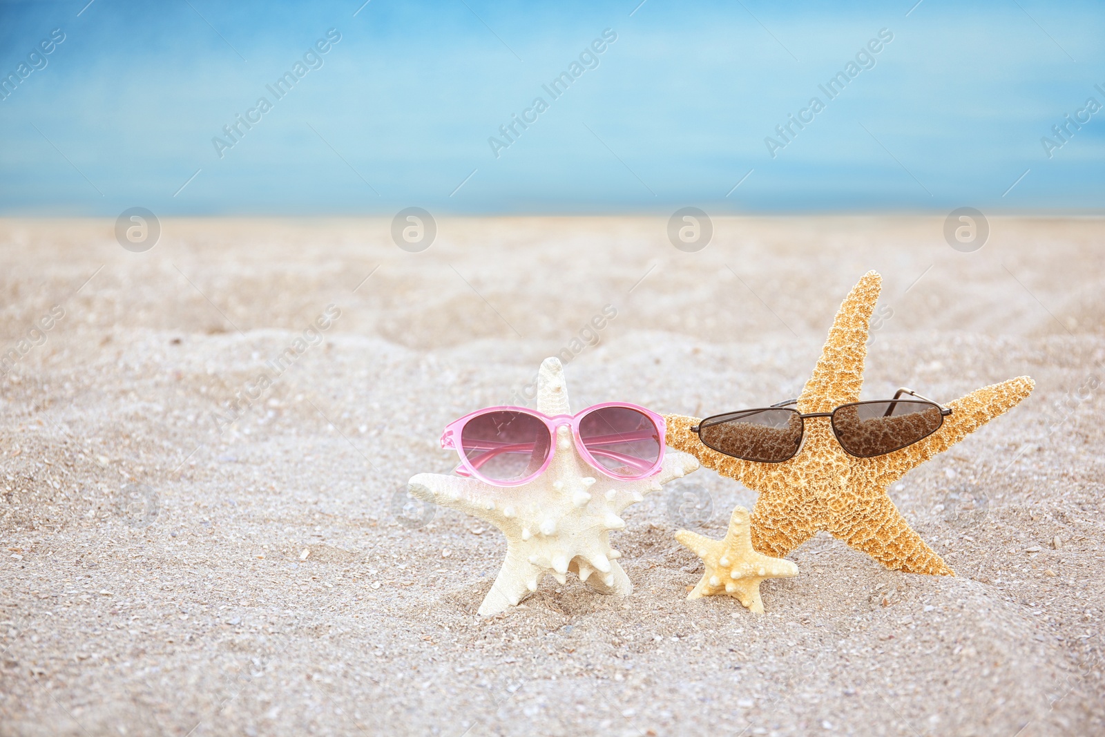 Photo of Starfish and sunglasses in sand on beach. Space for text