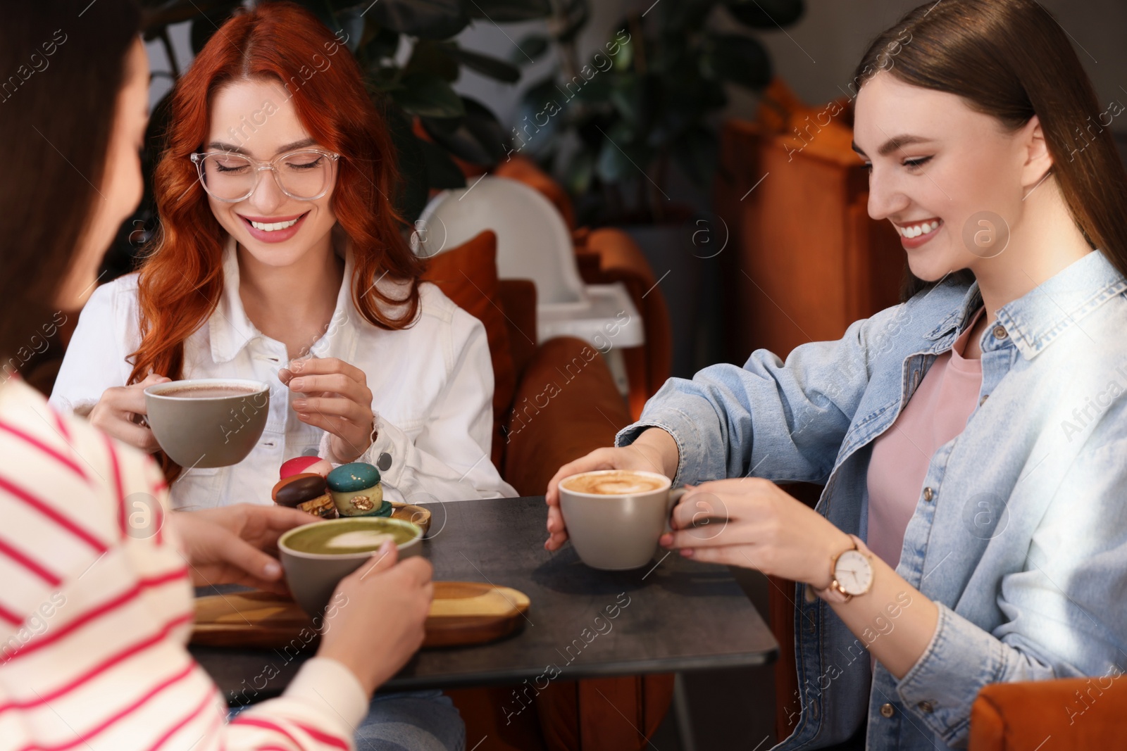 Photo of Happy friends talking and drinking coffee in cafe