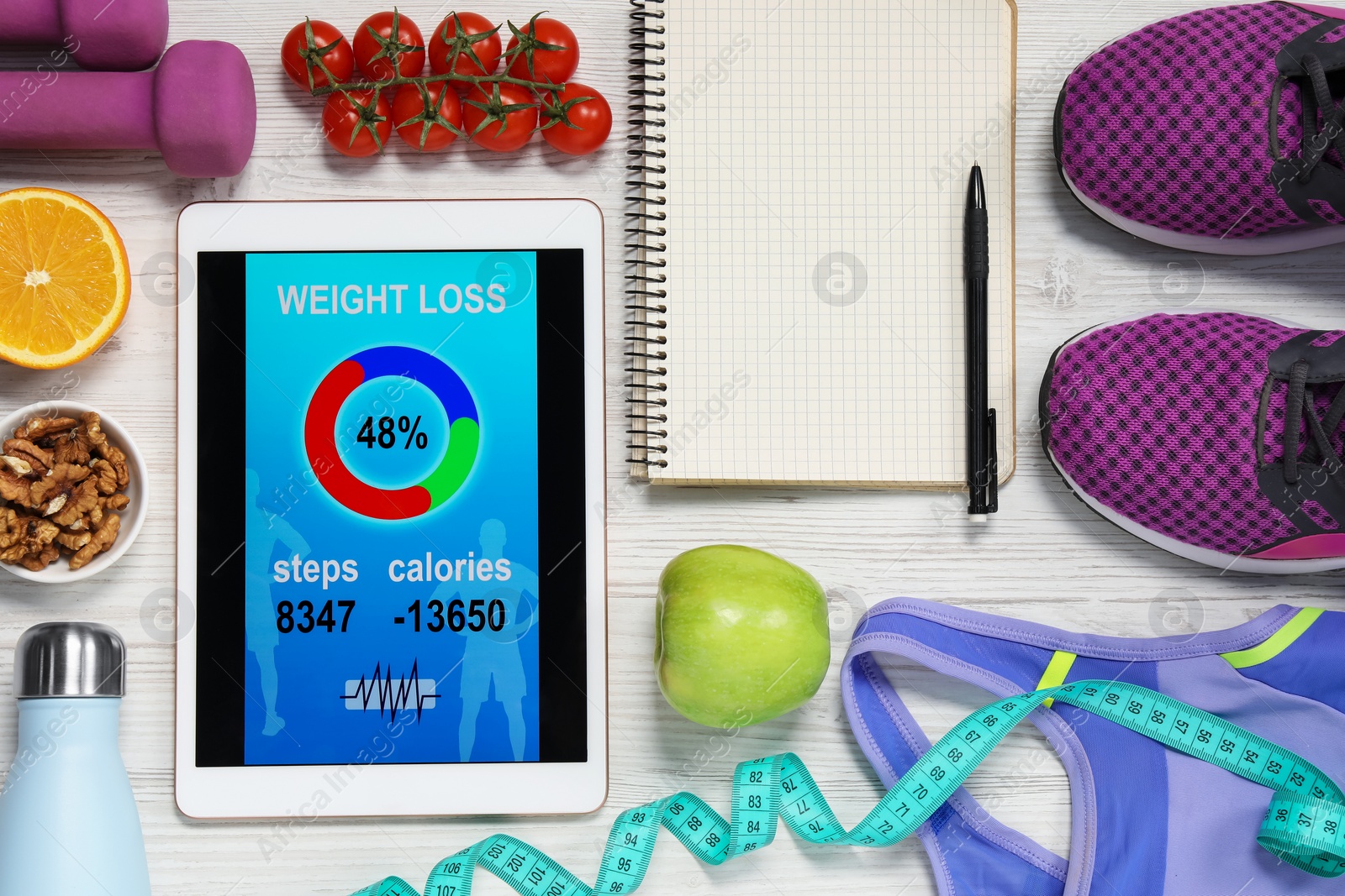 Photo of Tablet with weight loss calculator application, fitness items and different products on white wooden table, flat lay