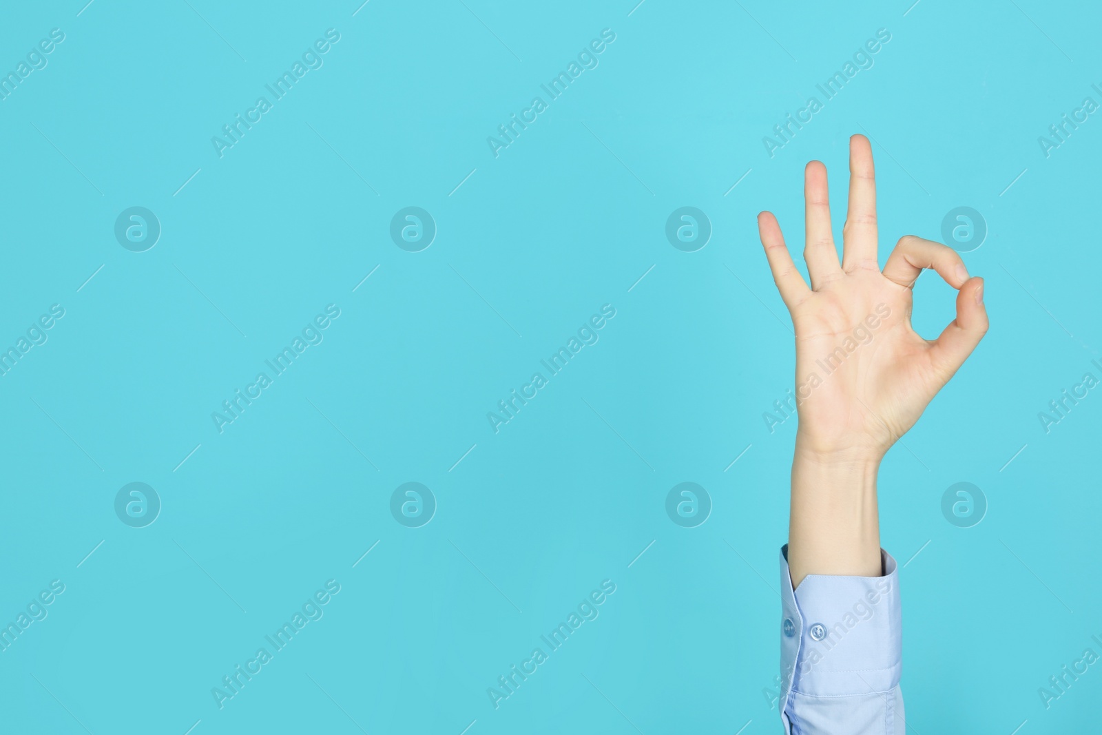 Photo of Young woman showing OK gesture on color background. Space for text