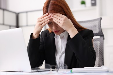 Photo of Woman suffering from headache at workplace in office