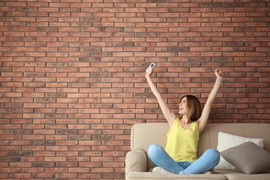 Happy woman with air conditioner remote at home