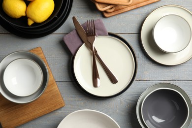 Photo of Set of clean dishware and lemons on grey wooden table, flat lay