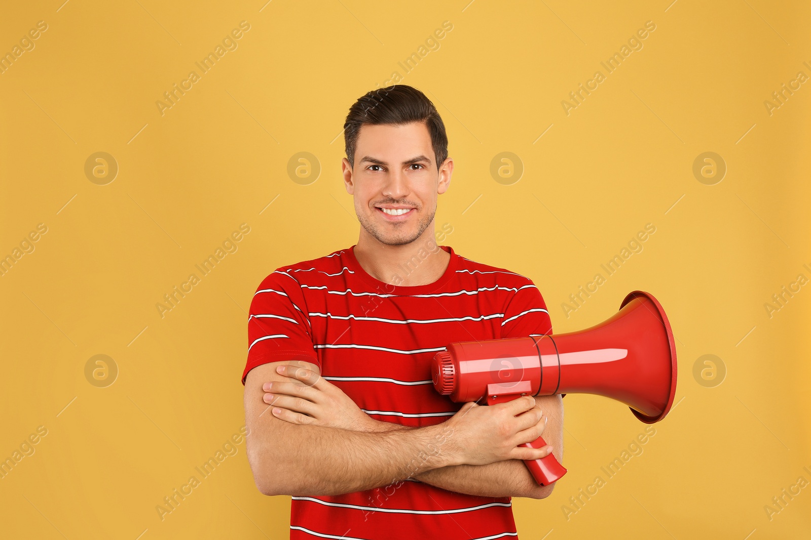 Photo of Handsome man with megaphone on yellow background