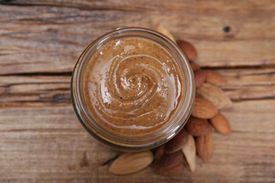 Tasty almond nut paste in jar on wooden table, top view