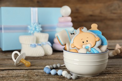 Photo of Cute tasty cookies of different shapes, toys and baby accessories on wooden table. Space for text
