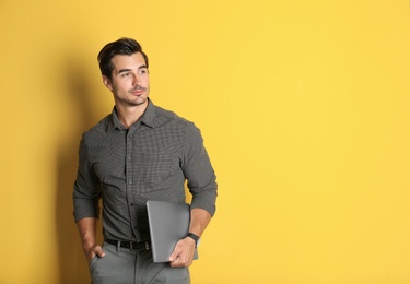 Young male teacher with laptop on yellow background. Space for text