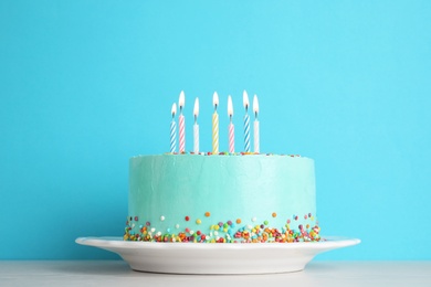 Photo of Fresh delicious birthday cake with candles on table against color background