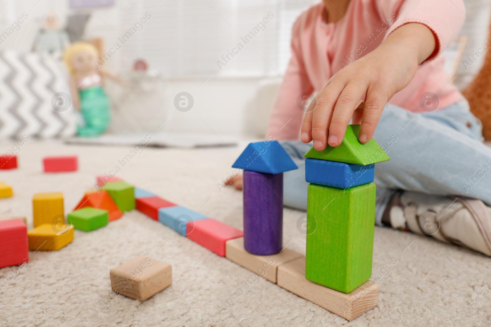 Photo of Cute little girl playing with colorful building blocks at home, closeup