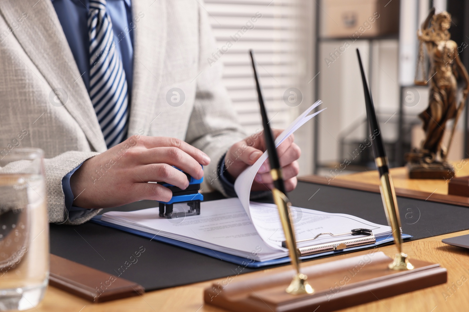 Photo of Notary stamping document at wooden table in office, closeup