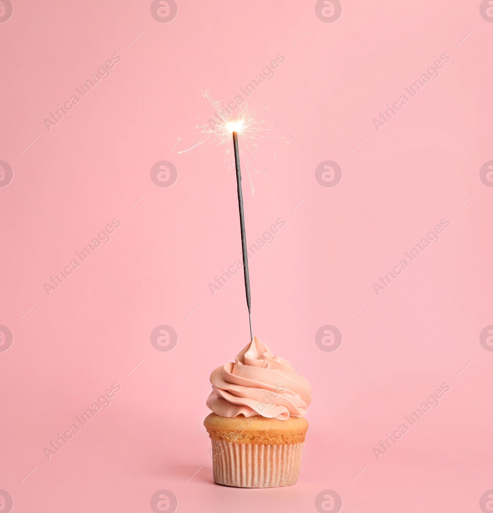 Photo of Birthday cupcake with sparkler on pink background