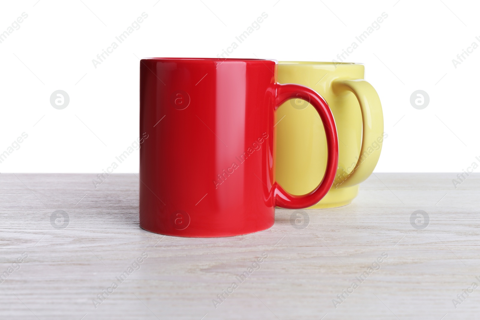 Photo of Ceramic mugs on wooden table against white background