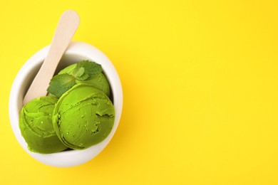 Tasty matcha ice cream in bowl on yellow background, top view. Space for text