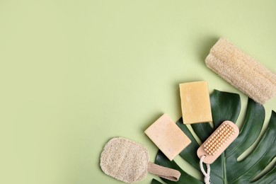 Photo of Eco friendly personal care products and leaf on light green background, flat lay. Space for text
