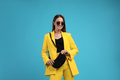 Photo of Fashionable young woman with stylish bag on light blue background