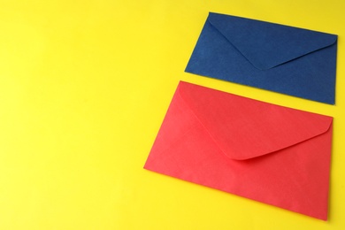 Photo of Colorful paper envelopes on yellow background. Space for text
