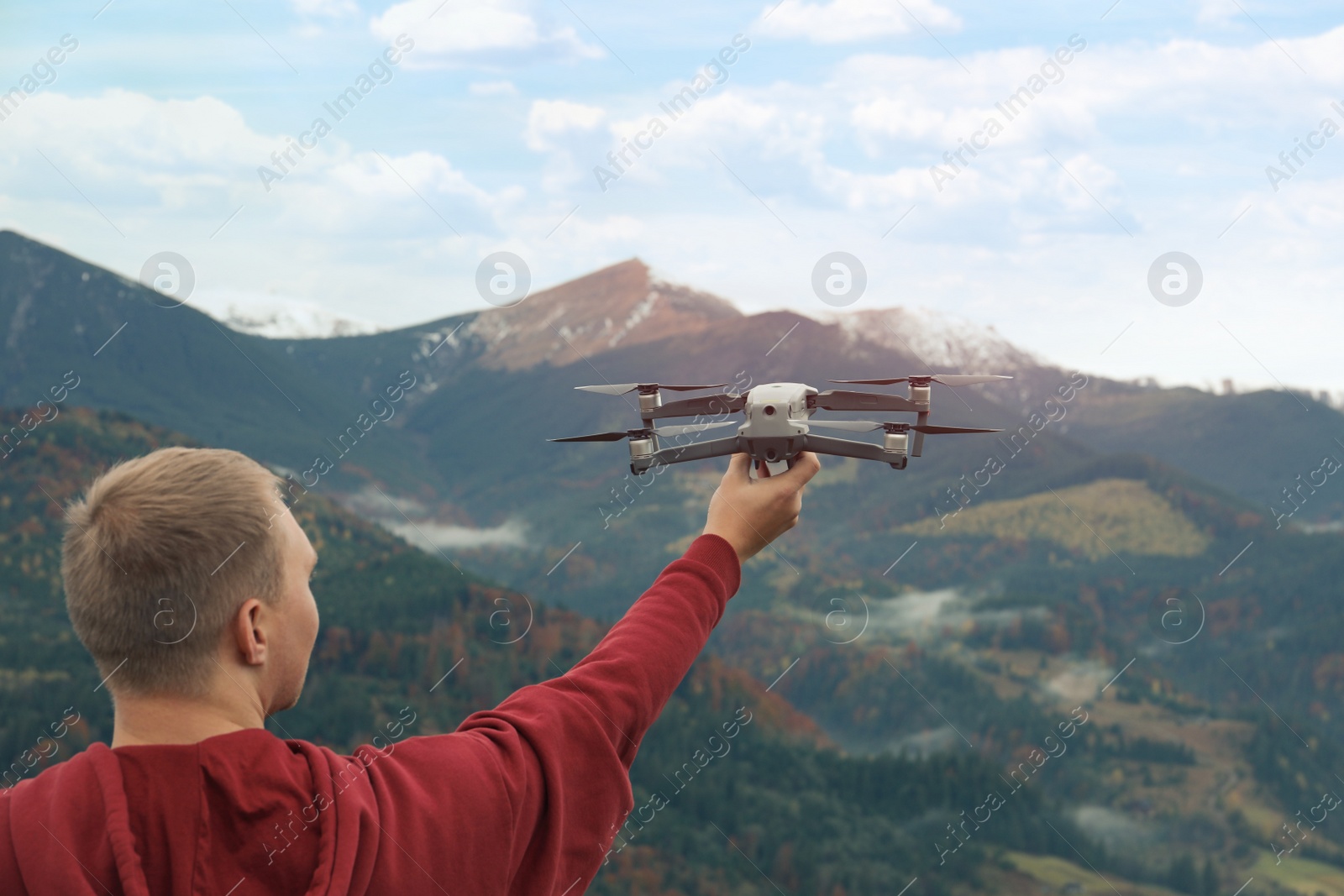 Photo of Young man with modern drone in mountains, back view