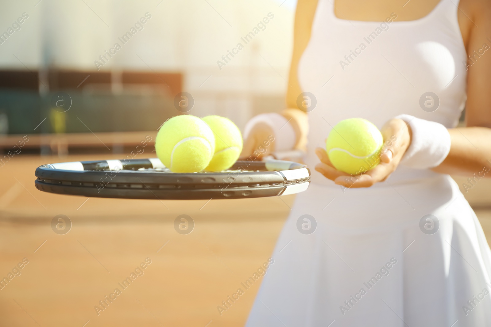 Photo of Sportswoman with racket and tennis balls at court, closeup