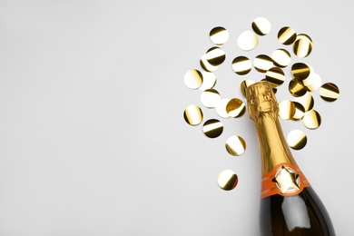 Photo of Flat lay composition with confetti and bottle of champagne on light background. Space for text