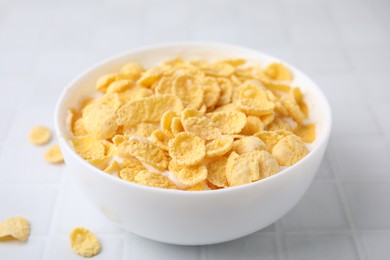 Photo of Breakfast cereal. Tasty corn flakes with milk in bowl on white tiled table, closeup