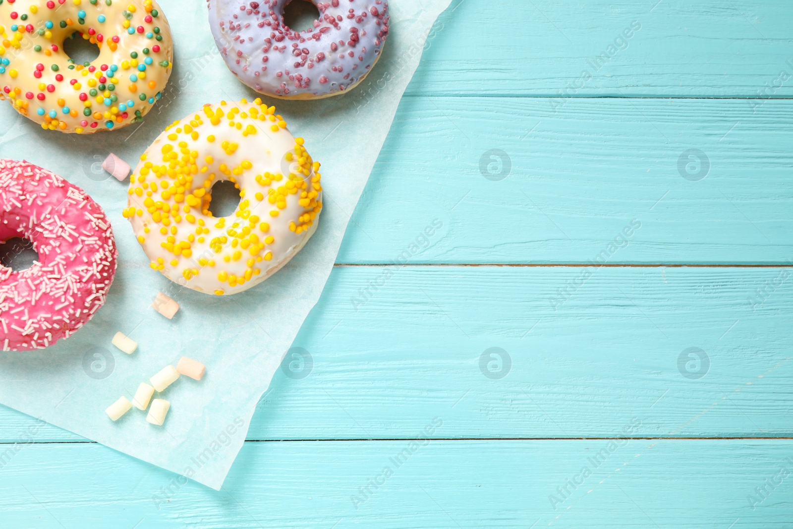 Photo of Delicious glazed donuts on blue wooden table, flat lay. Space for text