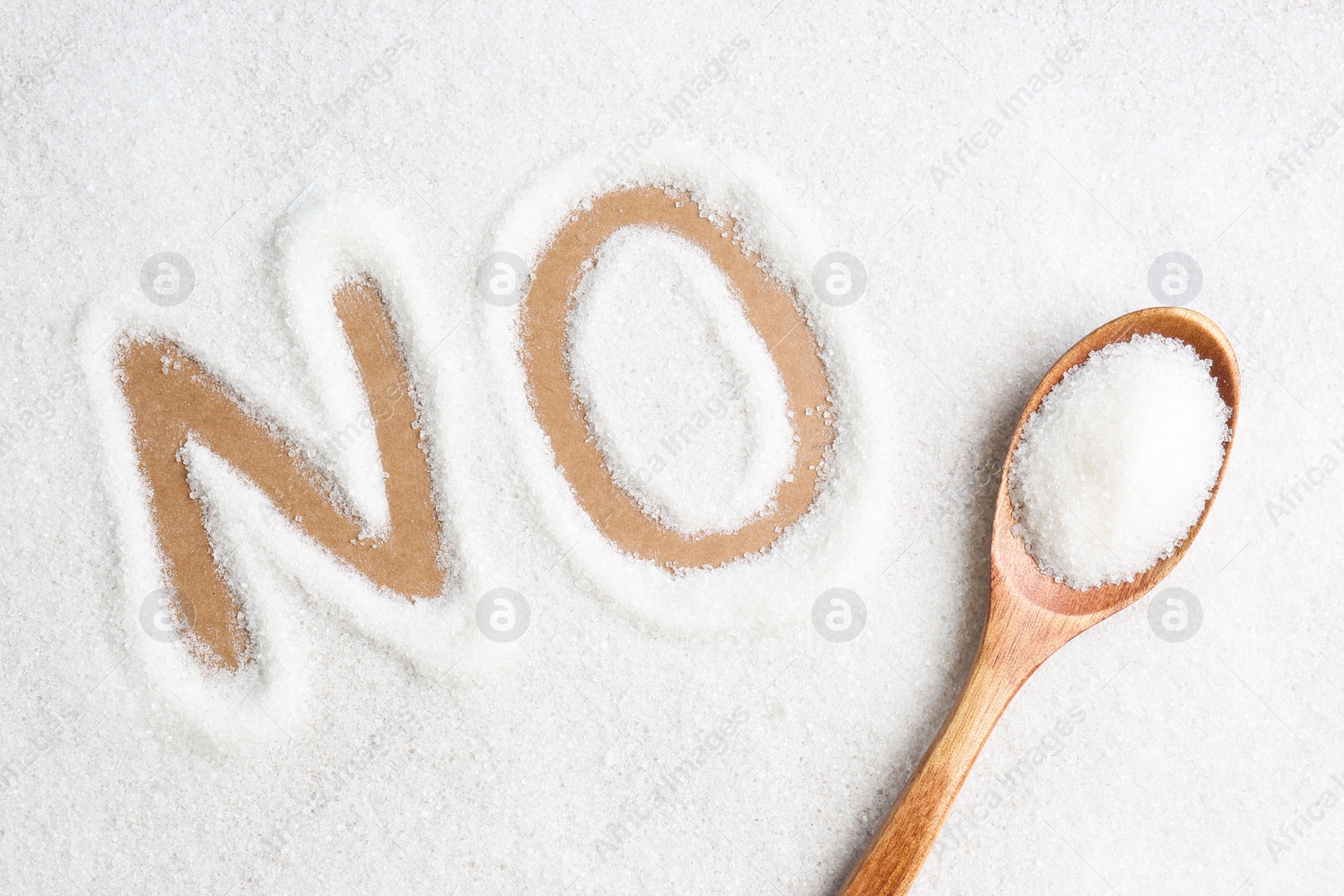 Photo of Word No made of sugar and wooden spoon on brown background, flat lay