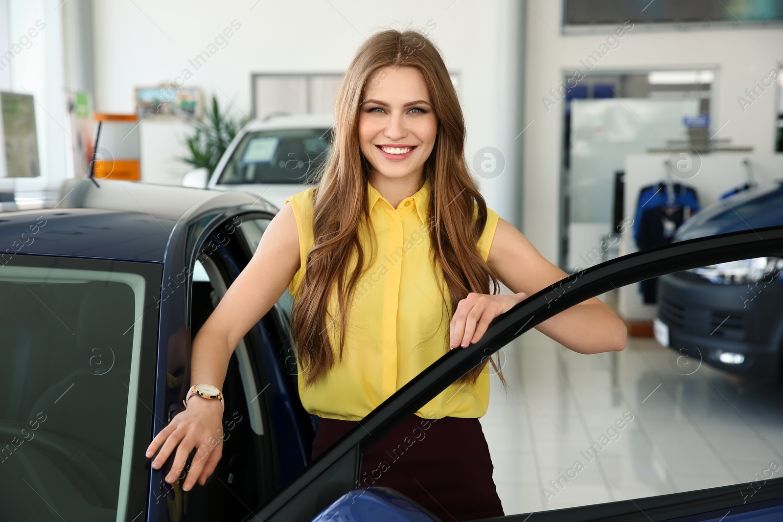 Photo of Young saleswoman near automobile in car dealership
