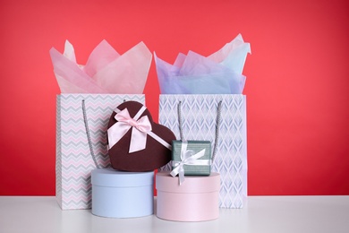 Shopping paper bags and gift boxes on red background