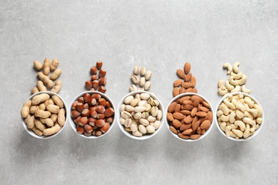 Photo of Flat lay composition with organic nuts on grey background, top view. Snack mix