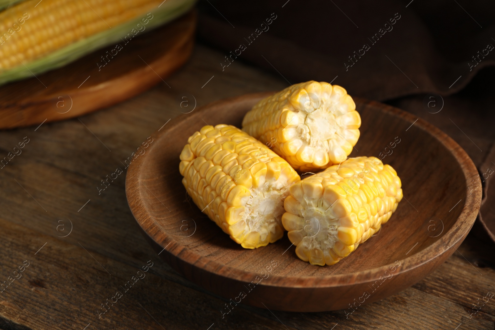 Photo of Tasty sweet corn cobs on wooden table, closeup