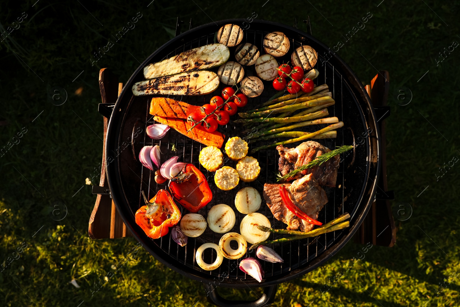 Photo of Delicious grilled vegetables and meat on barbecue grill outdoors, top view