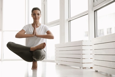 Photo of Young woman practicing toe stand asana in yoga studio. Padangusthasana pose