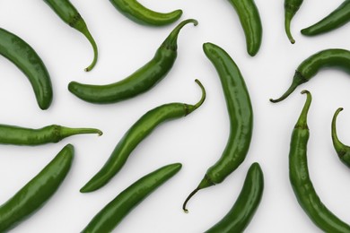 Many green hot chili peppers on white background, flat lay