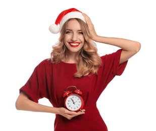 Photo of Happy young woman wearing Santa hat with alarm clock on white background. Christmas time