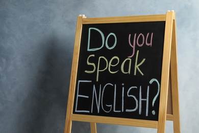 Photo of Blackboard with question Do You Speak English on grey background