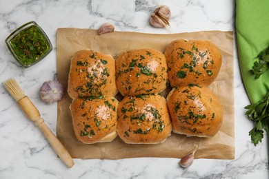 Photo of Traditional pampushka buns with garlic and herbs on white marble table, flat lay