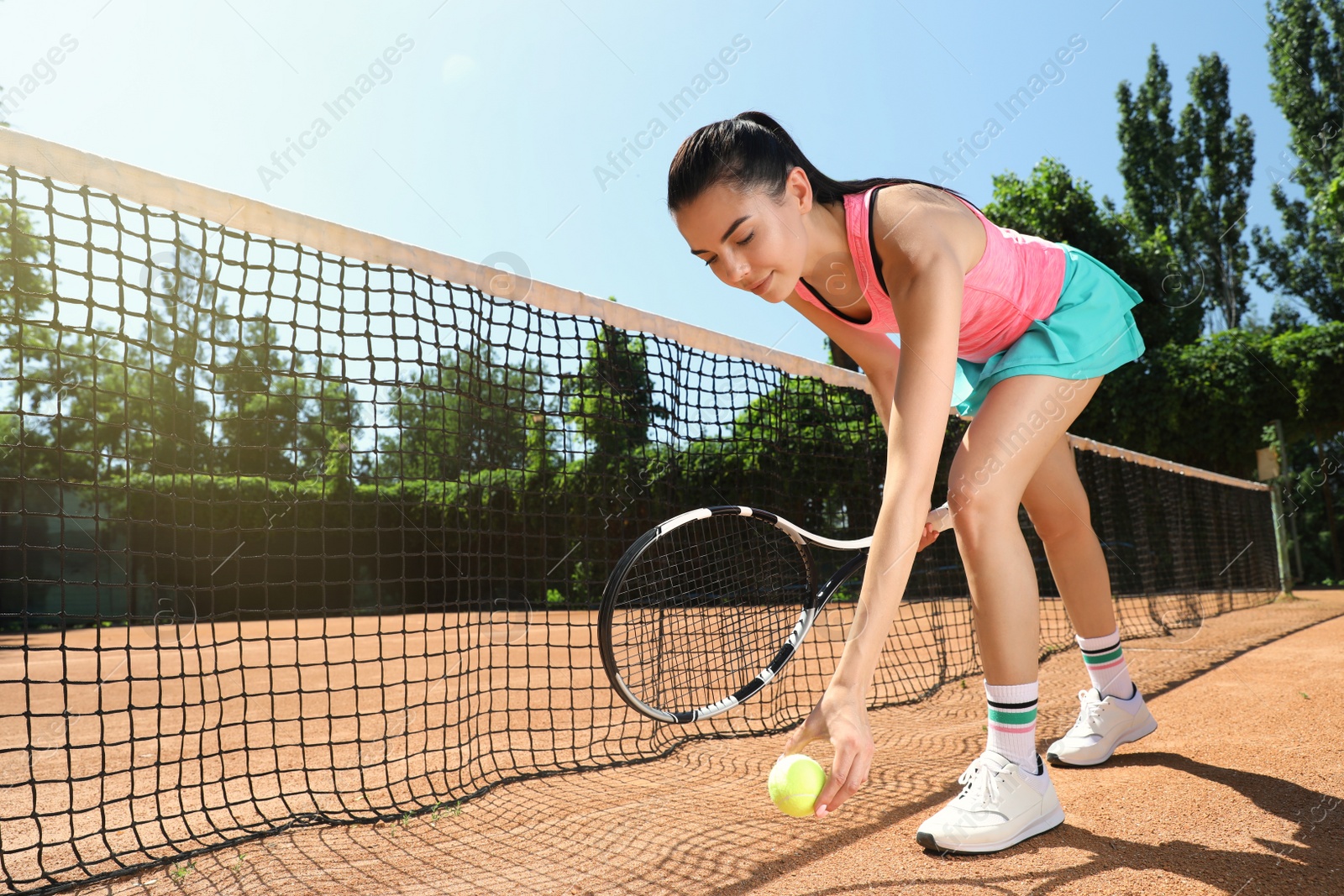 Photo of Woman picking up tennis ball on court