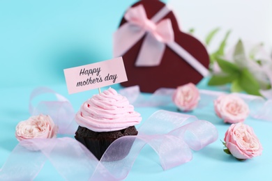 Photo of Festive surprise with tasty treat for Mother's Day on color background